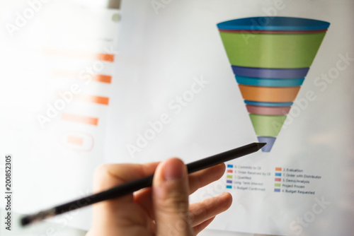 Male hand pointing with a finger at a sales funnel chart printed on a sheet of paper during a marketing meeting