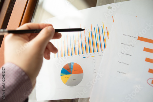 Male hand pointing with a finger at a sales funnel chart printed on a sheet of paper during a marketing meeting