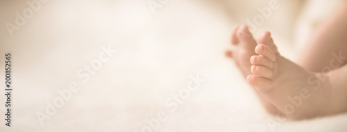 Newborn baby feet on creamy blanket. Mom and her child. Maternity, family, birth concept. Copy space for your text. Banner