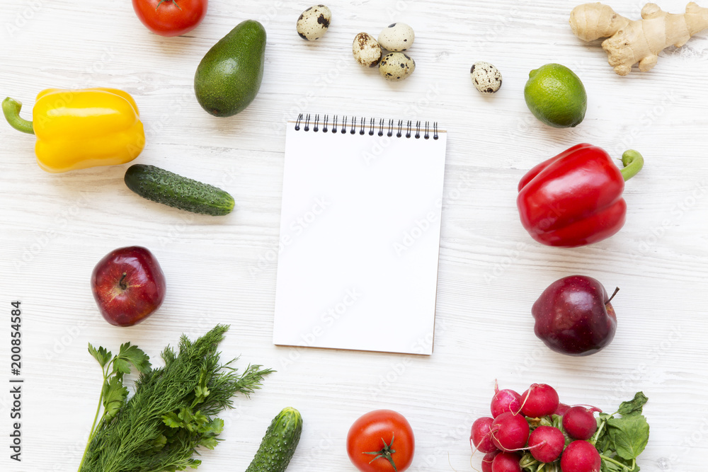 Set of raw food with notebook on white wooden background. Healthy food concept. Flat lay. Top view. From above. Set of raw food with notebook on white wooden background. Healthy food concept. Flat lay. Top view. From above.