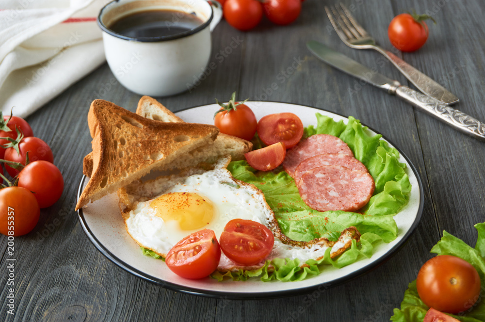 Fried egg, tomatoes, sausage, slices of bread and lettuce on a plate Fried egg, tomatoes, sausage, slices of bread and lettuce on a plate