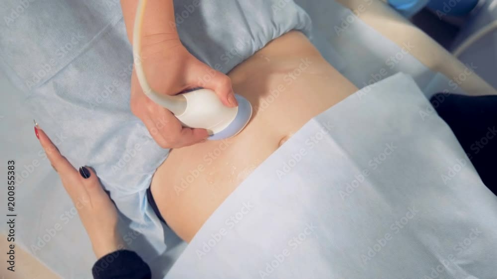 Ultrasonic sensory device is being passed across the belly of a pregnant woman