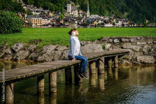 girl is sitting on wooden bridge. Young tourist woman sits on the bridge and enjoy the relaxation and freedom. Beautiful view of the mountain nature. wonderful view of Hallstatt. bridge over lake 