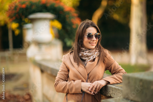 Stylish girl in a brown coat and a scarf with glasses. Using a phone in paris france. Makeup © Aleksandr