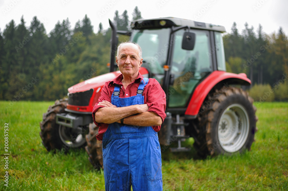 Proud farmer standing in front of his red tractor Stock Photo | Adobe Stock