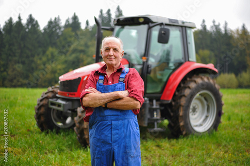 Proud farmer standing in front of his red tractor