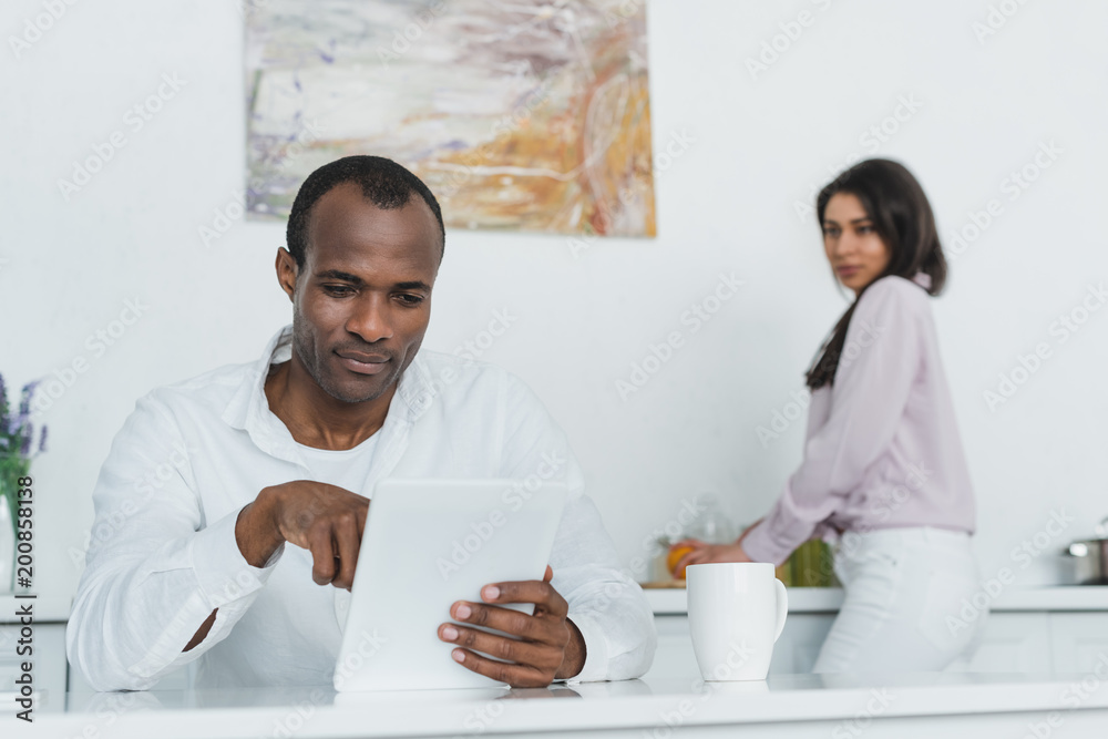 african american girlfriend cooking and boyfriend using tablet at kitchen african american girlfriend cooking and boyfriend using tablet at kitchen