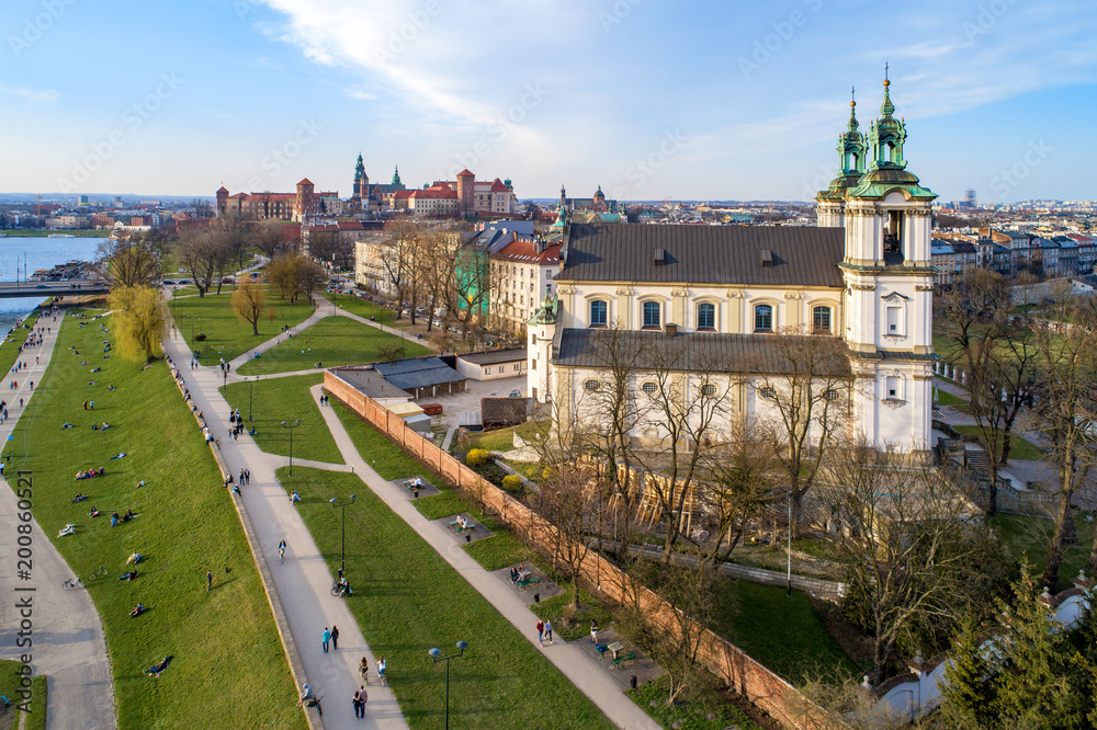 Krakow, Poland. Old city skyline, Paulinite monastery, Skalka church, far view of Wawel Cathedral and castle, Vistula River. People enjoying spring on the grass or walking. Aerial view, sunset light