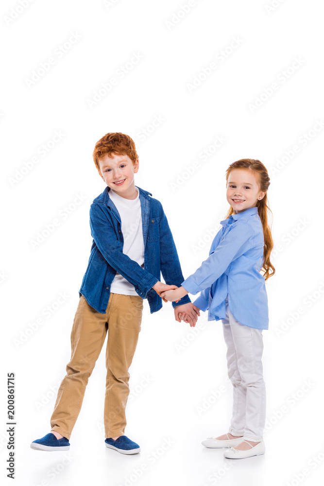 beautiful redhead siblings holding hands and smiling at camera isolated on white beautiful redhead siblings holding hands and smiling at camera isolated on white