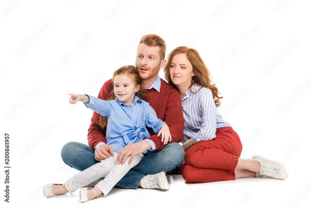 beautiful redhead family with one child sitting together and looking away isolated on white