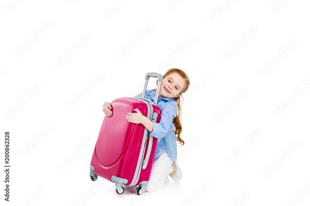 adorable happy child hugging pink suitcase isolated on white