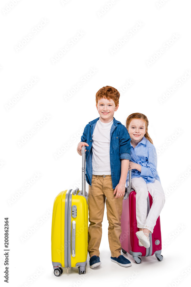 adorable happy redhead children with suitcases smiling at camera isolated on white adorable happy redhead children with suitcases smiling at camera isolated on white