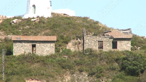 Lighthouse seamark on green stony rocks coastline beach in Japan Sea. Calmness and silence. Rest and tourism in beautiful place. Unique landscape and background.
