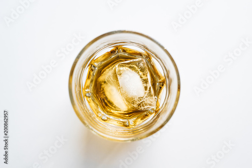 Glass of whiskey on ice from above on white background