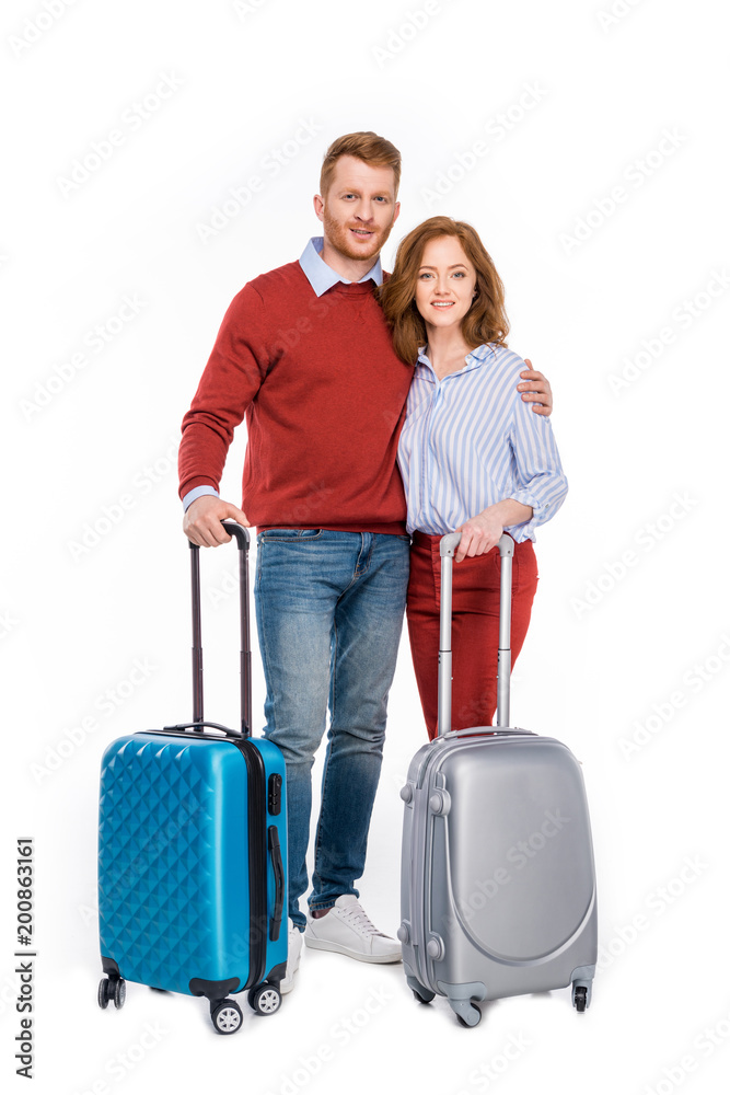 happy couple standing with suitcases and smiling at camera isolated on white happy couple standing with suitcases and smiling at camera isolated on white