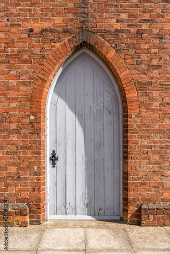 Old retro style white closed door on red brick wall of English building