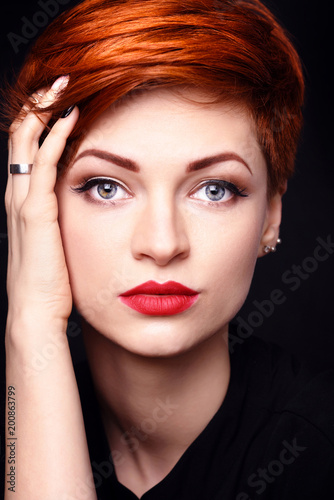 Portrait of a beautiful young red-haired woman with short hair on a dark background