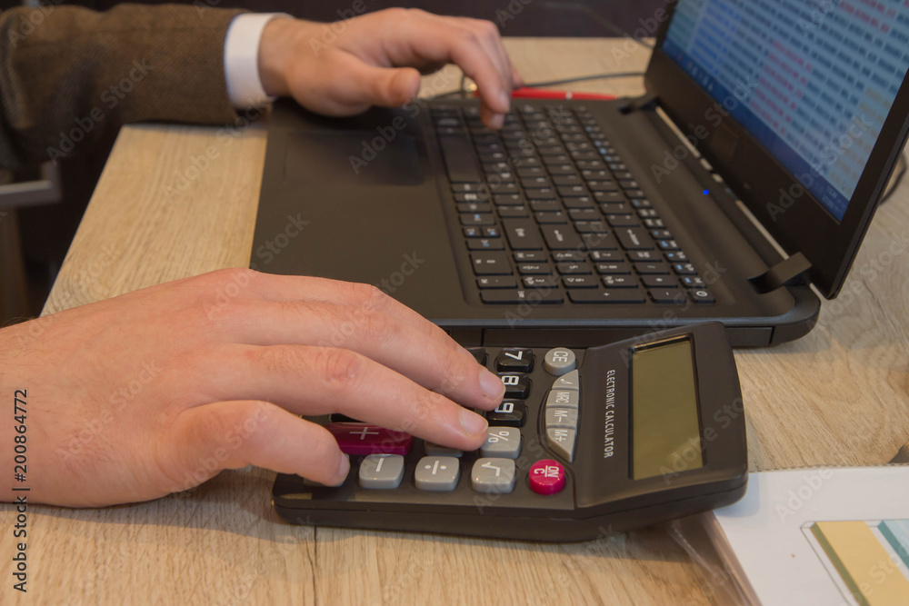 Corporate businessman working at office desk, he is using a calculator. Man doing his accounting, financial adviser working Corporate businessman working at office desk, he is using a calculator. Man doing his accounting, financial adviser working