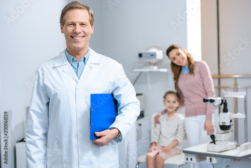 smiling handsome ophthalmologist looking at camera in consulting room