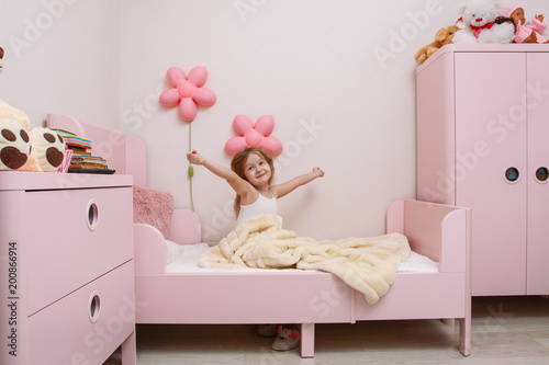 little girl wakes up in the morning in the children's bedroom