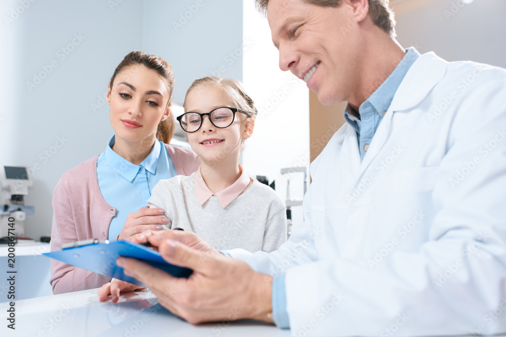 mother and daughter in glasses visiting oculist in clinic mother and daughter in glasses visiting oculist in clinic