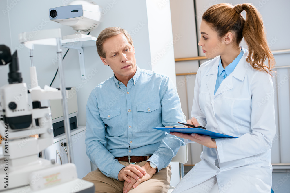 Obraz premium oculist writing diagnosis after examination of middle aged man