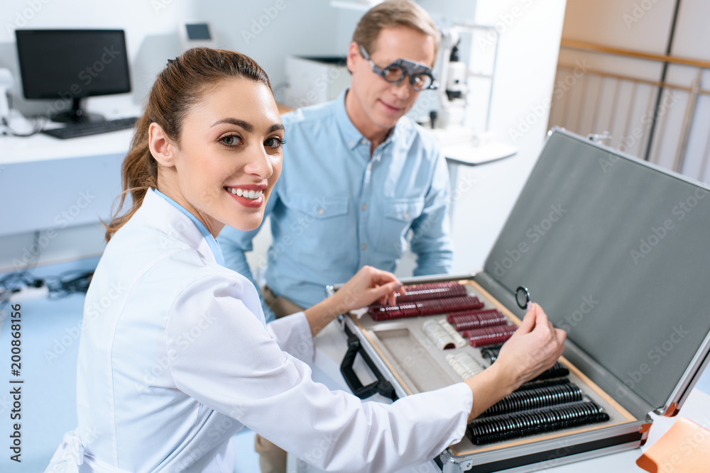 female optician examining middle aged man eyes with trial frame and lenses female optician examining middle aged man eyes with trial frame and lenses