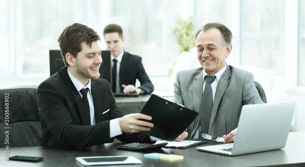 adult businessman discussing financial documents with a young colleague. adult businessman discussing financial documents with a young colleague.