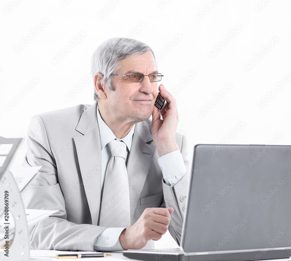 experienced businessman with mobile phone sitting at his Desk experienced businessman with mobile phone sitting at his Desk