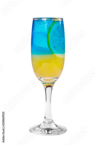A multi-colored, two-layered yellow and blue cocktail in a high glass with ice cubes with the taste of pineapple, orange and a slice of lemon. Side view. Isolated white background. Drink for the menu