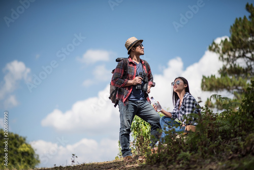 Thoughtful hiking couple looking away while relaxing in forest