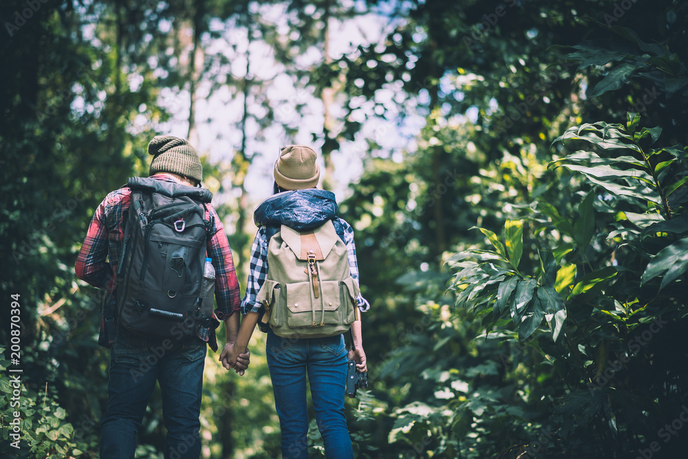 Young couple walking with backpacks in forest. Adventure hiking, Enjoy holidays together,