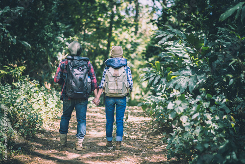 Young couple walking with backpacks in forest. Adventure hikes