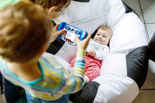 Two siblings kids boys taking picture with toy camera of cute baby girl.