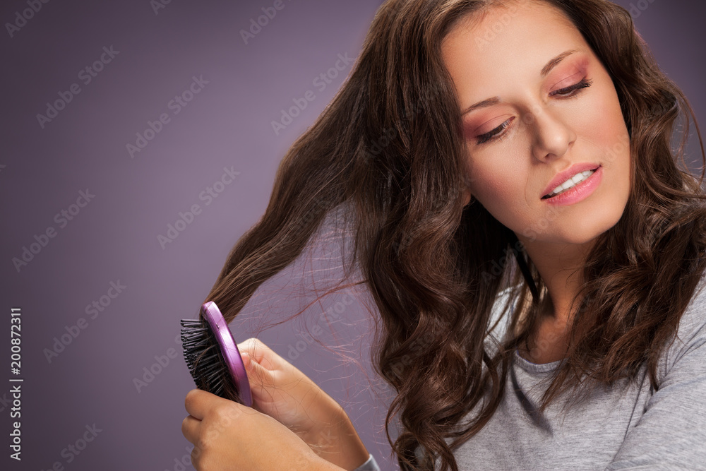 Beautiful woman combing her brown shiny hair Beautiful woman combing her brown shiny hair