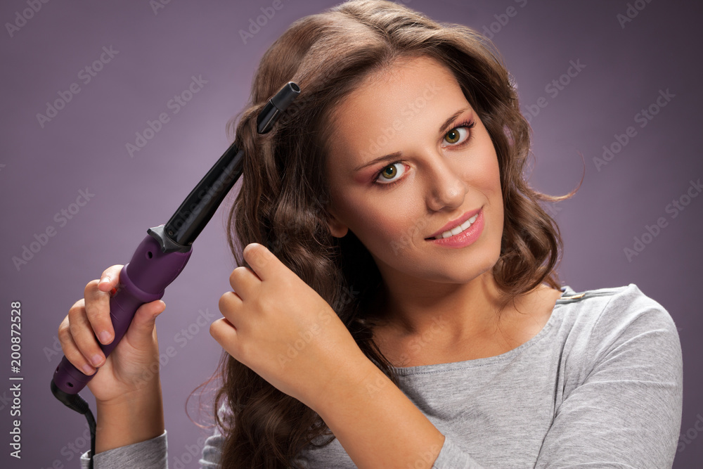 Beautiful woman using curling iron Beautiful woman using curling iron