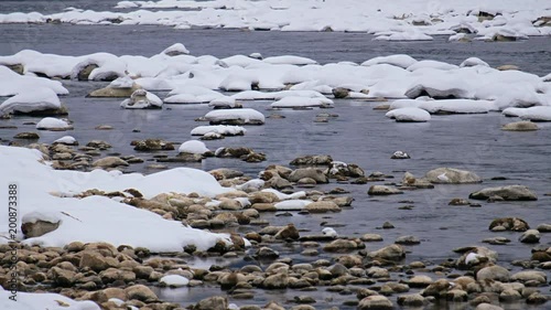 Stones with snow caps in the water of Altai Biya river in winter season photo