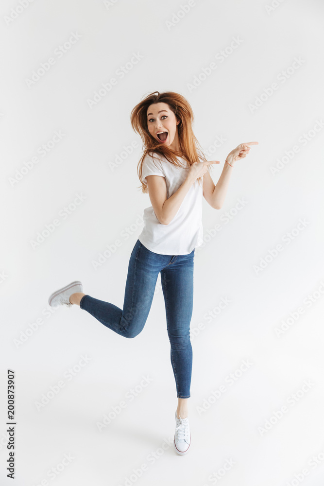 Full length image of Shocked happy woman in t-shirt jumping Full length image of Shocked happy woman in t-shirt jumping