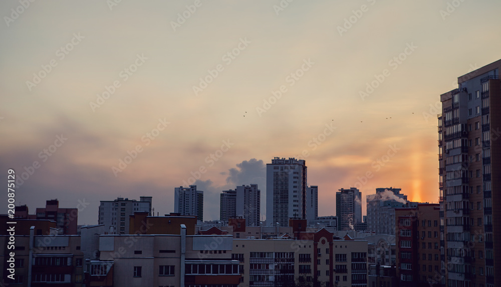 Panoramic view of beautiful yellow golden sunset over city. Evening urban landscape covered in setting sun beams.