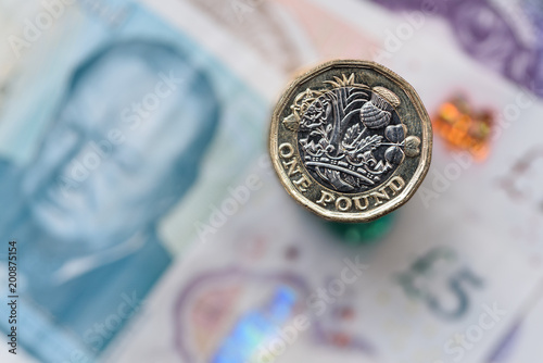 A close up of a British Pound Coin on top of bank notes photo