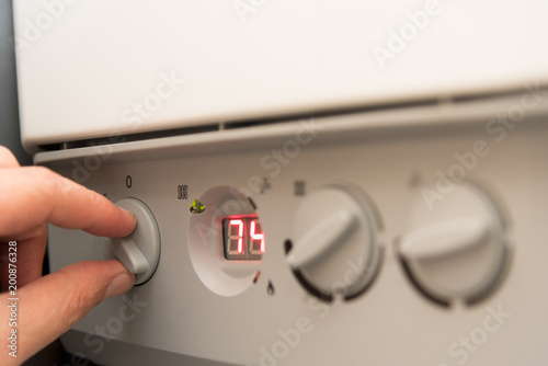 Fingers of a adult man turning on a British Combi Gas Boiler photo