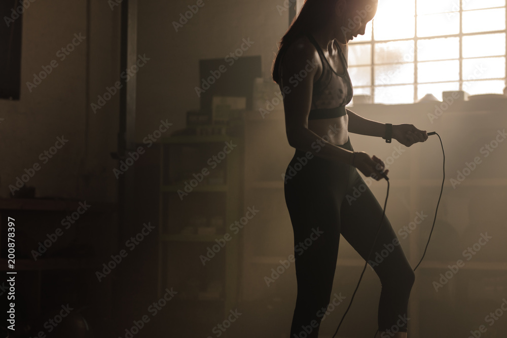 Female exercising with skipping rope at gym - obrazy, fototapety, plakaty 