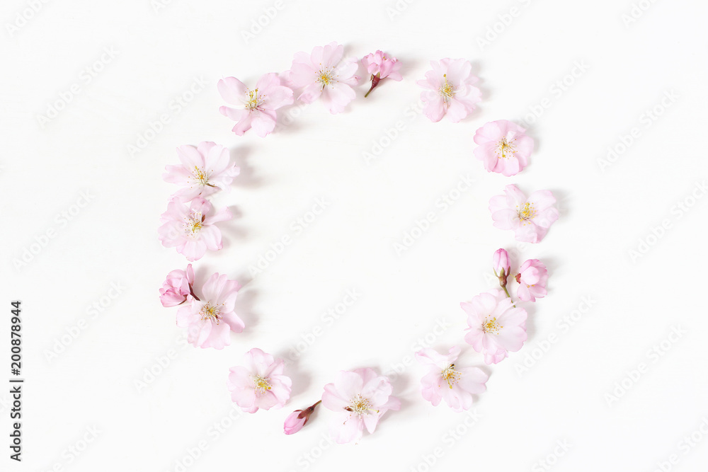 Fototapeta premium Styled stock photo. Spring, Easter feminine scene floral composition. Round frame wreath pattern made of pink Japanese cherry blossoms. White background. Flat lay, top view.