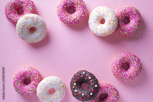Pink and white donuts with celebration item on pink background