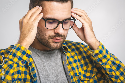 People, crisis, emotions and stress concept - unhappy man suffering from head ache at home. White background.