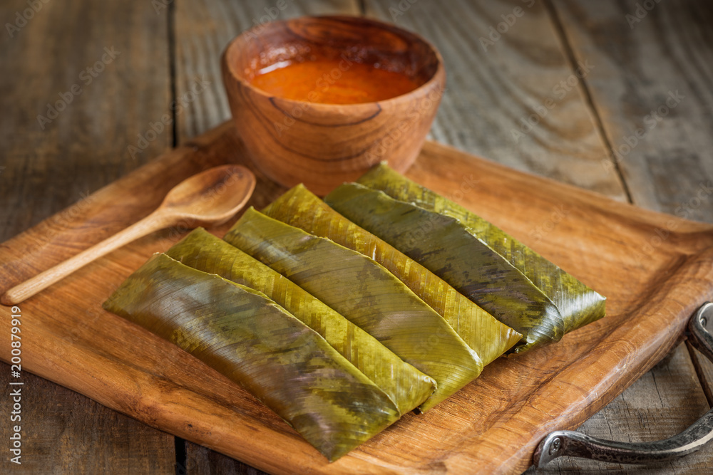 Foto de sticky rice wrapped in leaves and served with peanut sauce ...
