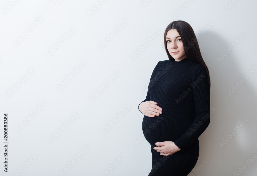 pregnant women in black dress on background white wall pregnant women in black dress on background white wall