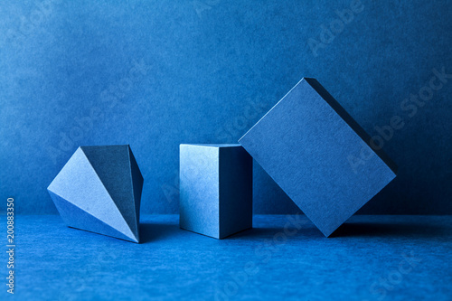 Geometrical figures still life composition. Three-dimensional prism pyramid tetrahedron rectangular cube objects on blue background. Platonic solids figures, simplicity concept photography. photo