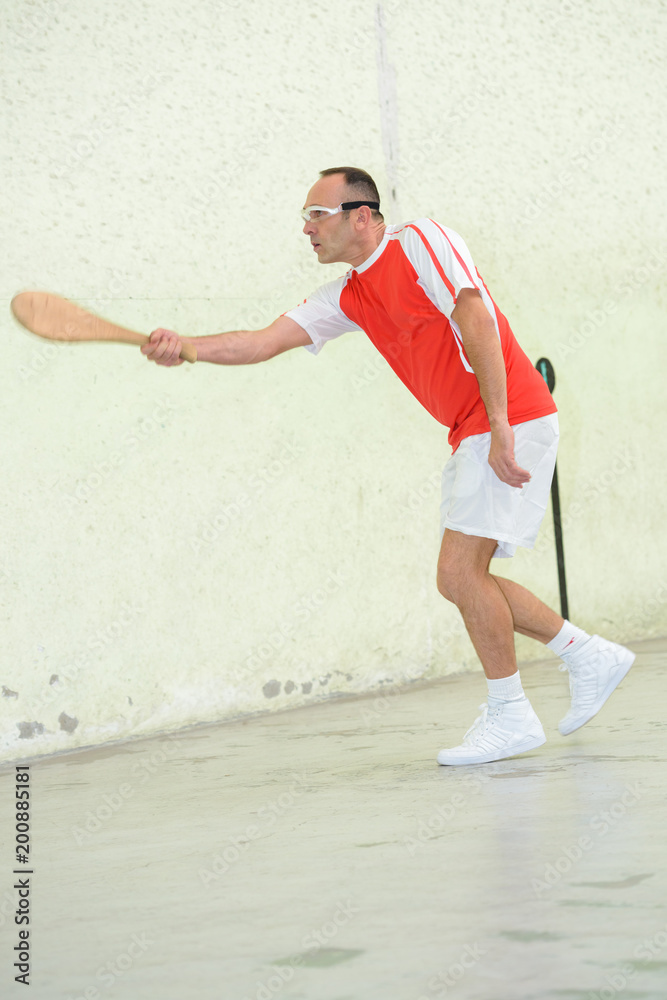 man playing squash with a wood racket man playing squash with a wood racket