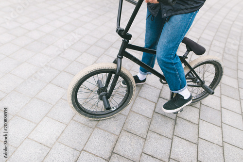 A young chelovek sits on a BMX bike. BMX with legs close-up. BMX concept. Street culture photo